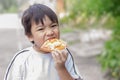 AsianÃ¢â¬â¹ childÃ¢â¬â¹ boyÃ¢â¬â¹ biting andÃ¢â¬â¹ eatingÃ¢â¬â¹ aÃ¢â¬â¹ hamburger.